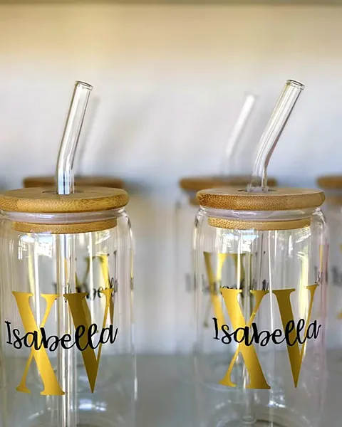 Two glass can cups with bamboo lids and glass straws, personalized with a gold XV monogram and the name Isabella